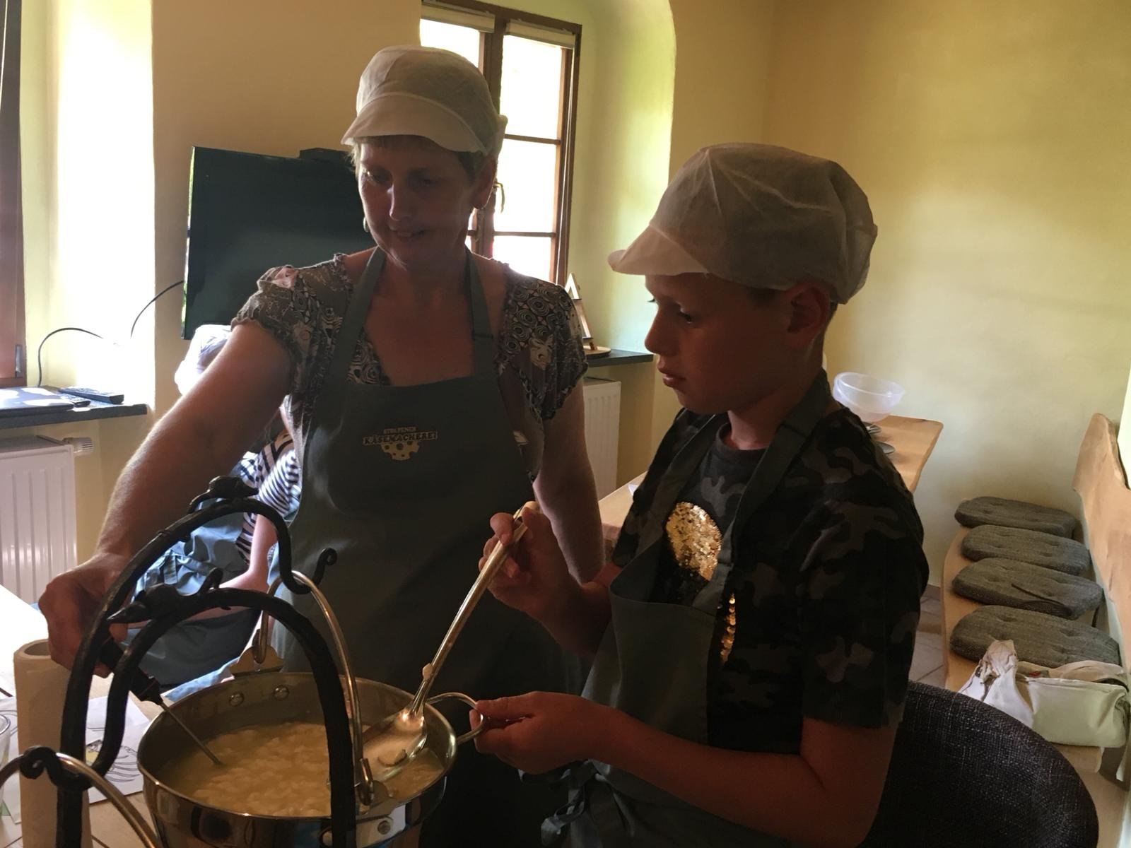 Petra zeigt am Kupferkessel, wie handwerklicher Käse entsteht