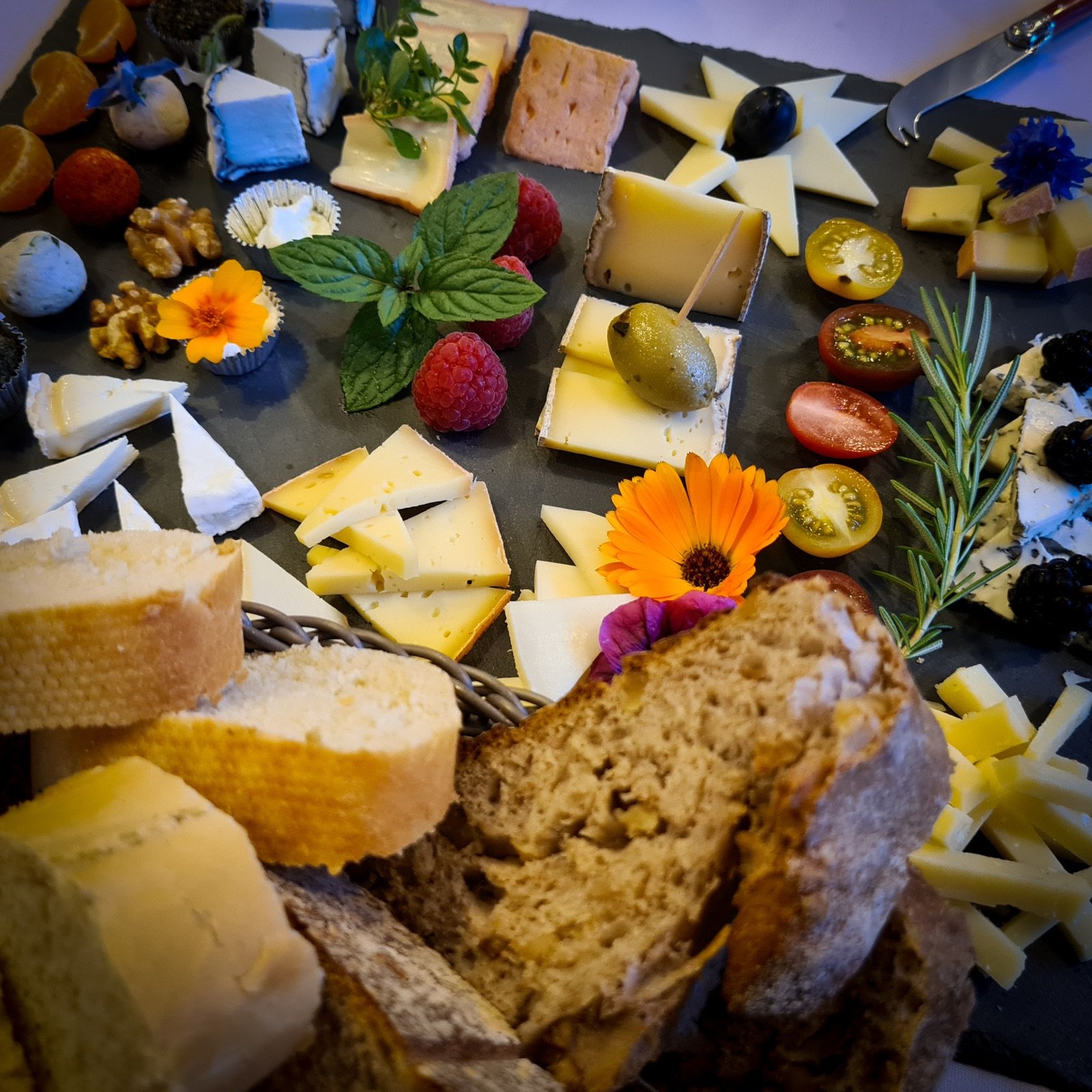 Käse-Brot-Brett mit verschiedenen Sorten, Blüten und frischem Brot