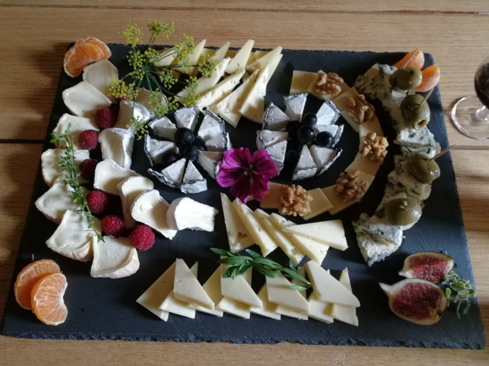 Schieferplatte mit kunstvoll angerichteten Käsesorten, Feigen und Mandarinen